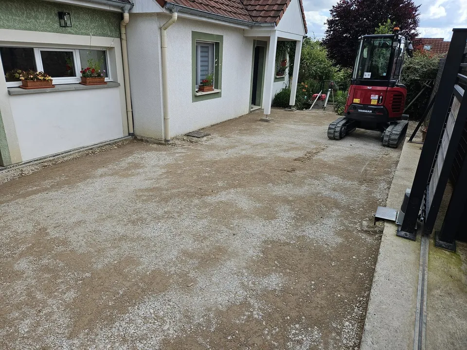 Rénovation d'une cour en béton désactivé avec pavés comprenant, le nivellement de la plate-forme, pose de pavés en pierre naturelle, pose de caniveaux et béton désactivé de couleur dalmatien.